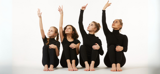  Four dancers of different ages pose with their arms up. 