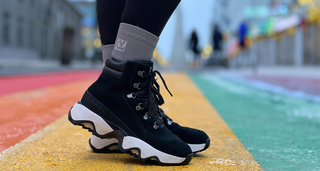 Woman wearing grey compression socks for women on rainbow painted street